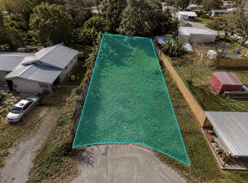 An aerial view shows a vacant, grass-covered residential lot highlighted in teal — 1131 FLEMING AVENUE, LAKELAND, FL
