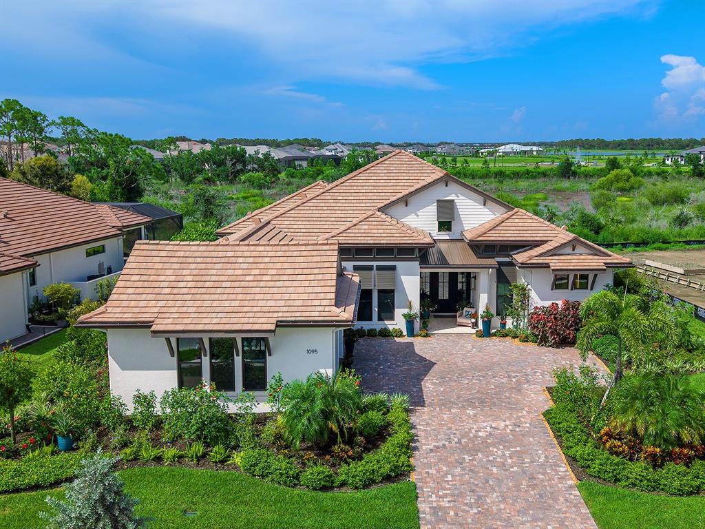 An aerial view of a single-story house with a tiled roof and brick paver driveway — 1095 BLUE SHELL LOOP, SARASOTA, FL