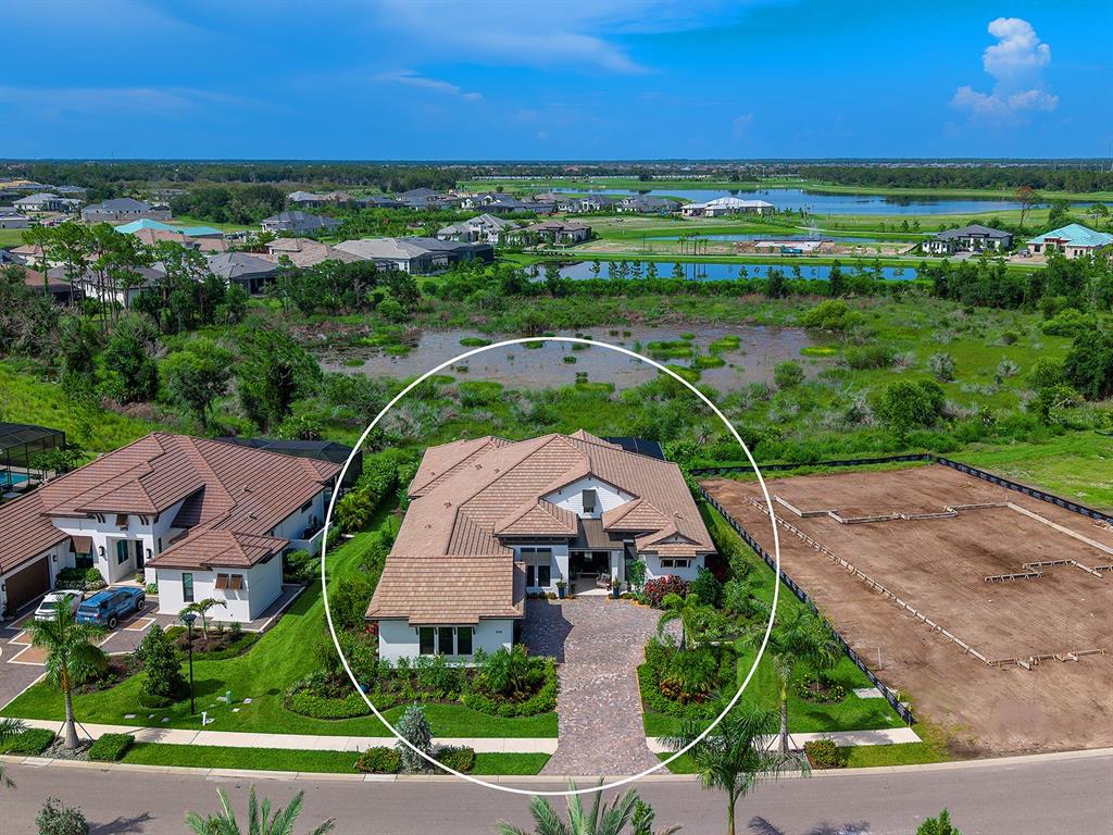 An aerial view shows a single-family home with a tiled roof and a paved driveway — 1095 BLUE SHELL LOOP, SARASOTA, FL