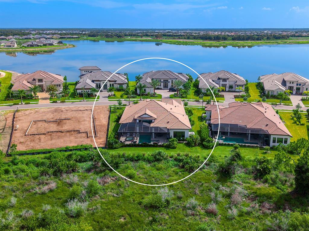 An aerial view shows a residential house with a pool and screened lanai near water — 1095 BLUE SHELL LOOP, SARASOTA, FL