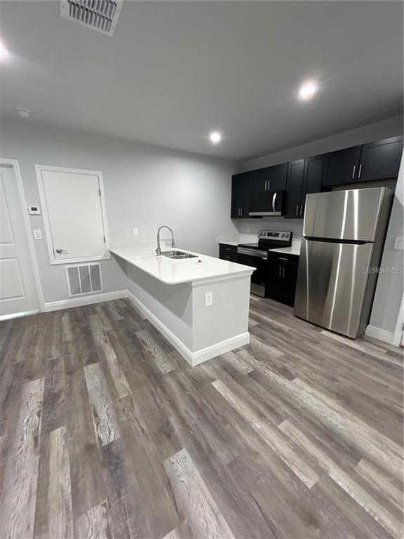A modern kitchen features dark cabinets, stainless steel appliances, and a white quartz island countertop — 1813 PUFFIN STREET UNIT 1813, SEBRING, FL