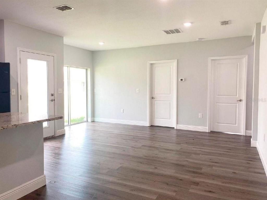 An interior view of a room with wood-look flooring, two white doors, and a glass door — 1813 PUFFIN STREET UNIT 1813, SEBRING, FL