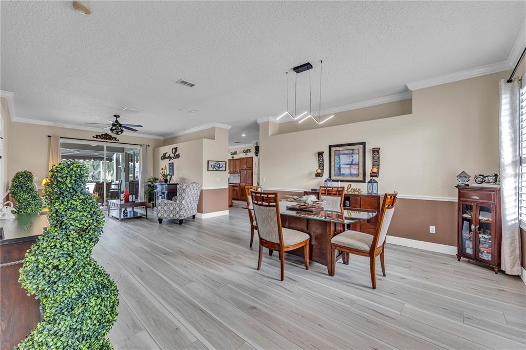 A dining area with a glass table and modern light fixture opens to a living space — 255 STRATHMORE CIRCLE, KISSIMMEE, FL