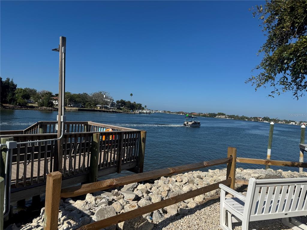 A wooden dock and a white bench overlook a waterway with a passing boat — 61 5TH AVENUE, VENICE, FL