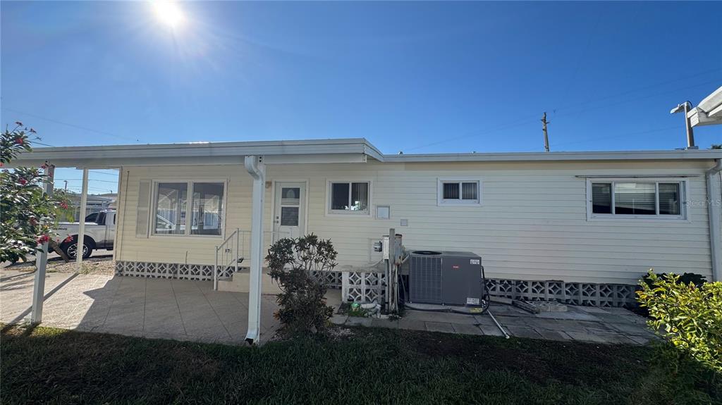 The exterior of a light-colored mobile home features a concrete patio and an air conditioner — 61 5TH AVENUE, VENICE, FL