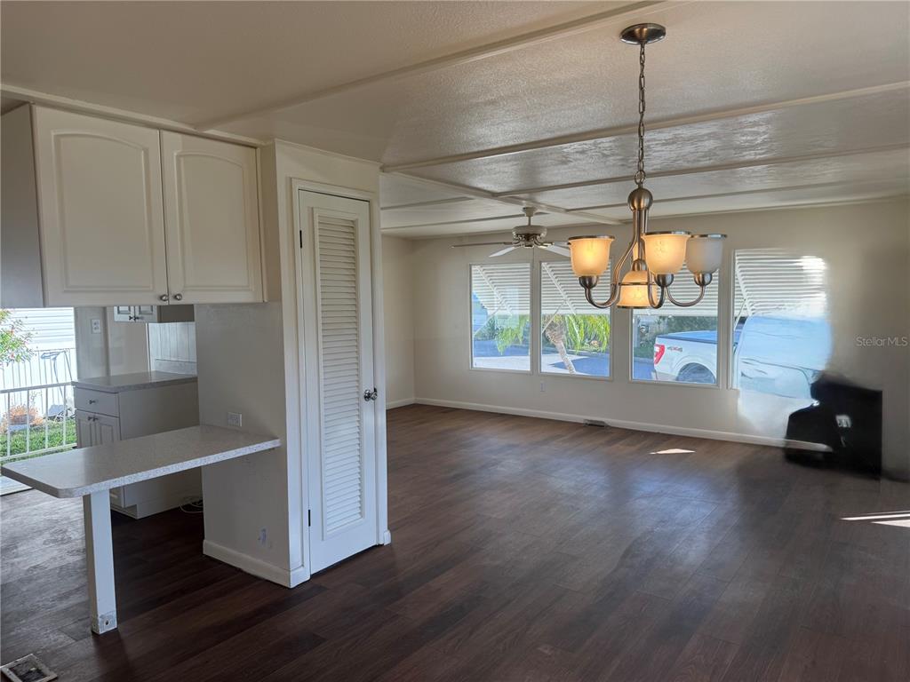 A kitchen with white cabinets and a breakfast bar opens into a dining area — 61 5TH AVENUE, VENICE, FL