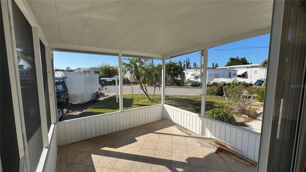 A screened-in porch with tiled flooring overlooks a street and neighboring mobile homes — 61 5TH AVENUE, VENICE, FL