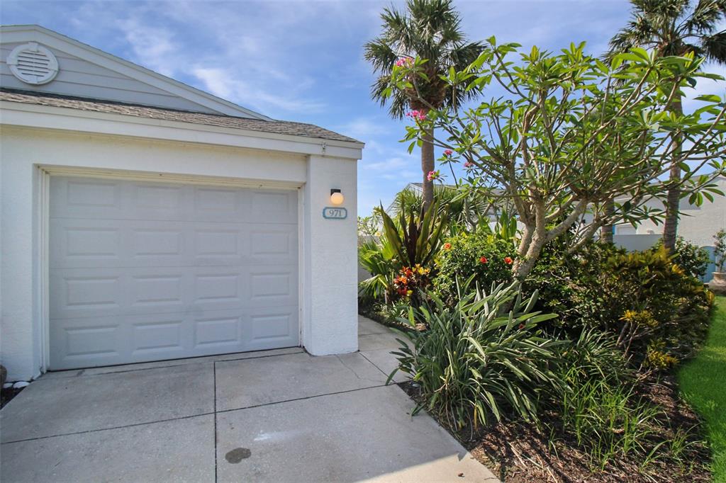 A white garage door with a house number sign next to a landscaped garden area — 971 WATERSIDE LANE, BRADENTON, FL