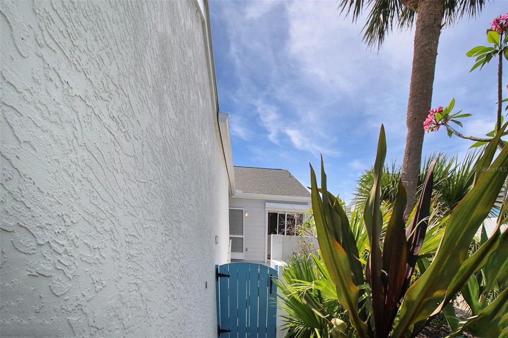 A blue wooden gate leads to a white house exterior with a palm tree nearby — 971 WATERSIDE LANE, BRADENTON, FL