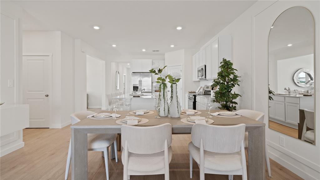 A dining area with a wooden table and chairs sits in front of a kitchen — 5399 WHISPERING GARDEN WAY, CLERMONT, FL