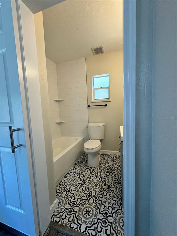 A bathroom features a white bathtub, dark blue subway tile, and patterned floor tiles — 260 20TH AVENUE S, ST PETERSBURG, FL