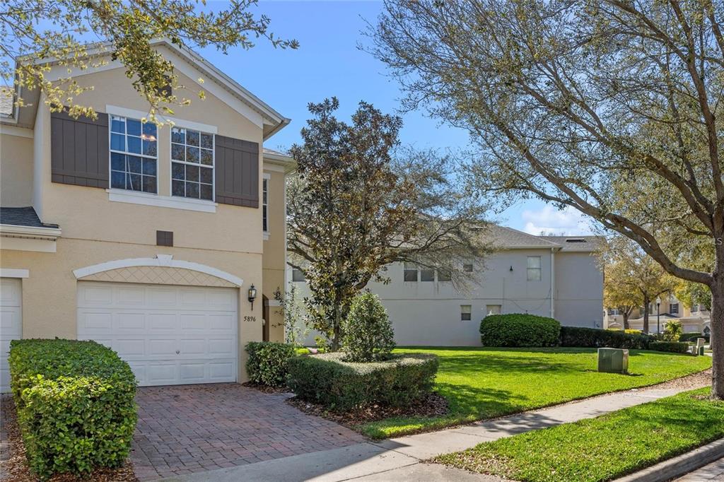 A two-story townhouse with a beige stucco exterior, a single-car garage, and a paved driveway — 5896 STRADA CAPRI WAY, ORLANDO, FL