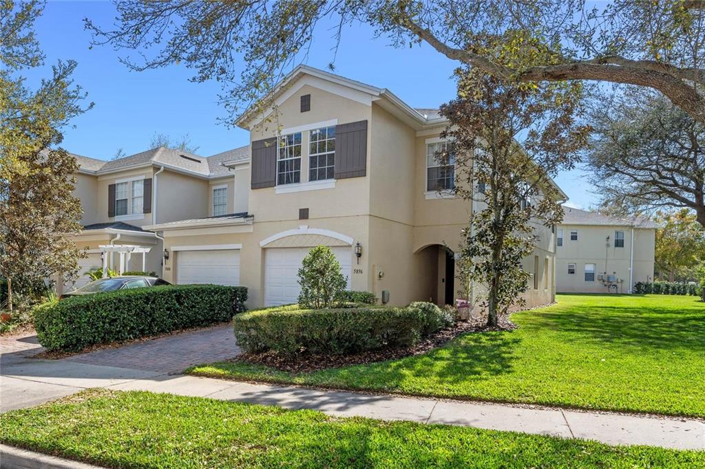 A two-story tan stucco townhouse with a two-car garage and a manicured front lawn — 5896 STRADA CAPRI WAY, ORLANDO, FL