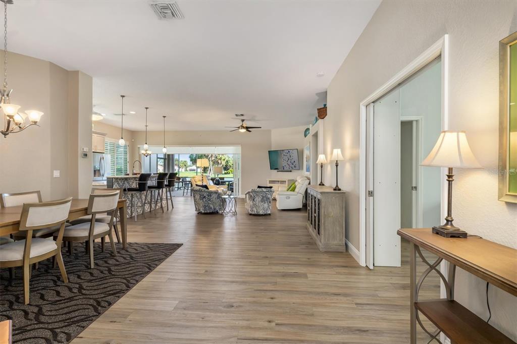 An open-concept living and dining area features wood-look flooring, a kitchen island, and sliding doors — 26238 FEATHERSOUND DRIVE, PUNTA GORDA, FL