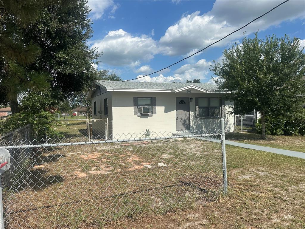 A single-story house with light-colored siding and a chain-link fence in the front yard — 640 N 8TH STREET, EAGLE LAKE, FL