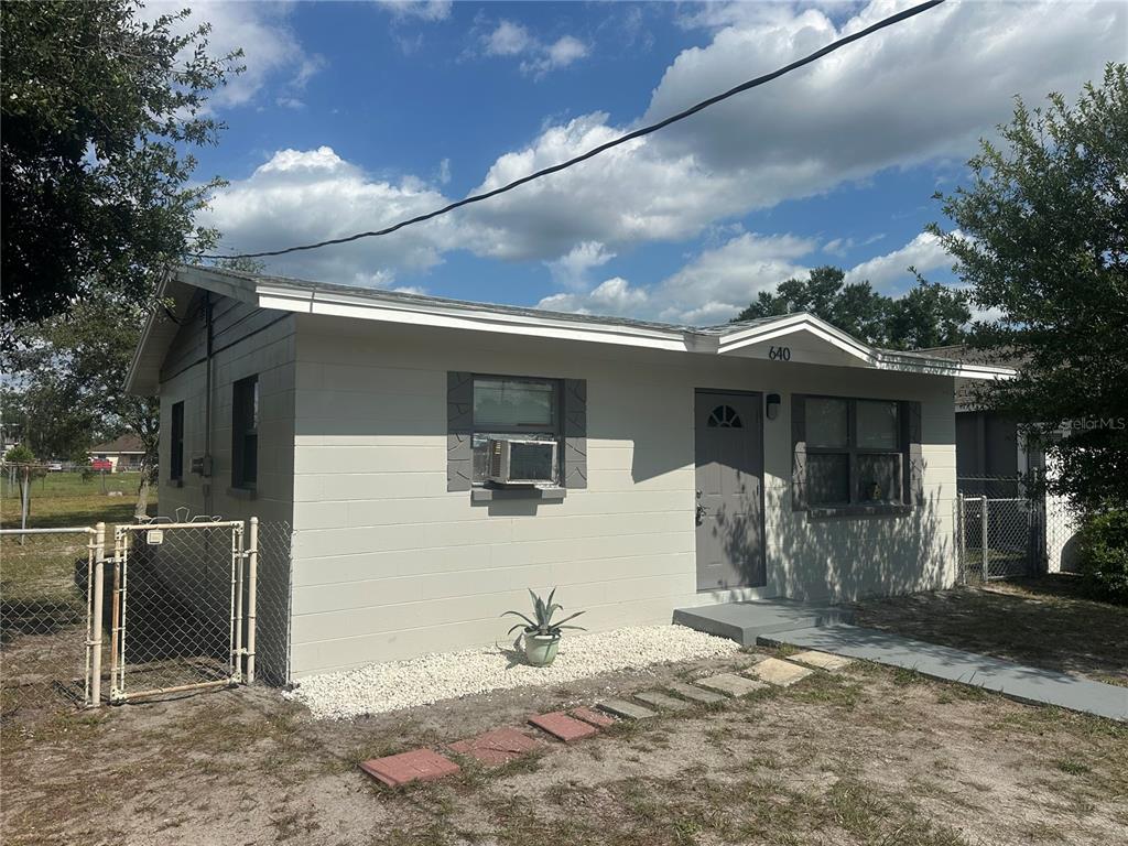 A single-story concrete block house with a gray door, window shutters, and a chain-link fence — 640 N 8TH STREET, EAGLE LAKE, FL
