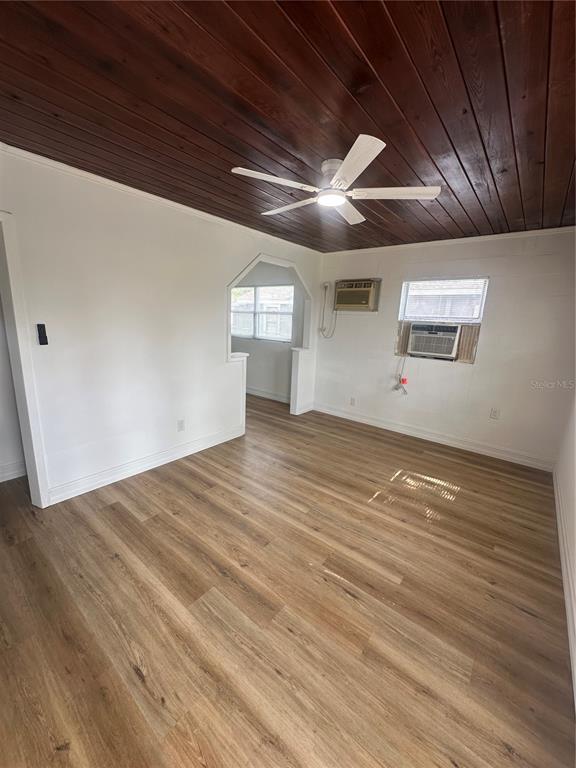 A living room with wood-paneled ceiling, light wood-look flooring, and a window air conditioning unit — 640 N 8TH STREET, EAGLE LAKE, FL