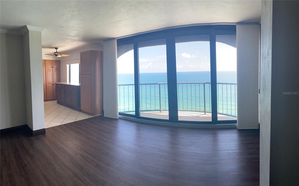 A living area with dark wood flooring leads to a balcony overlooking the ocean — 3003 S ATLANTIC AVENUE UNIT 21B4, DAYTONA BEACH SHORES, FL