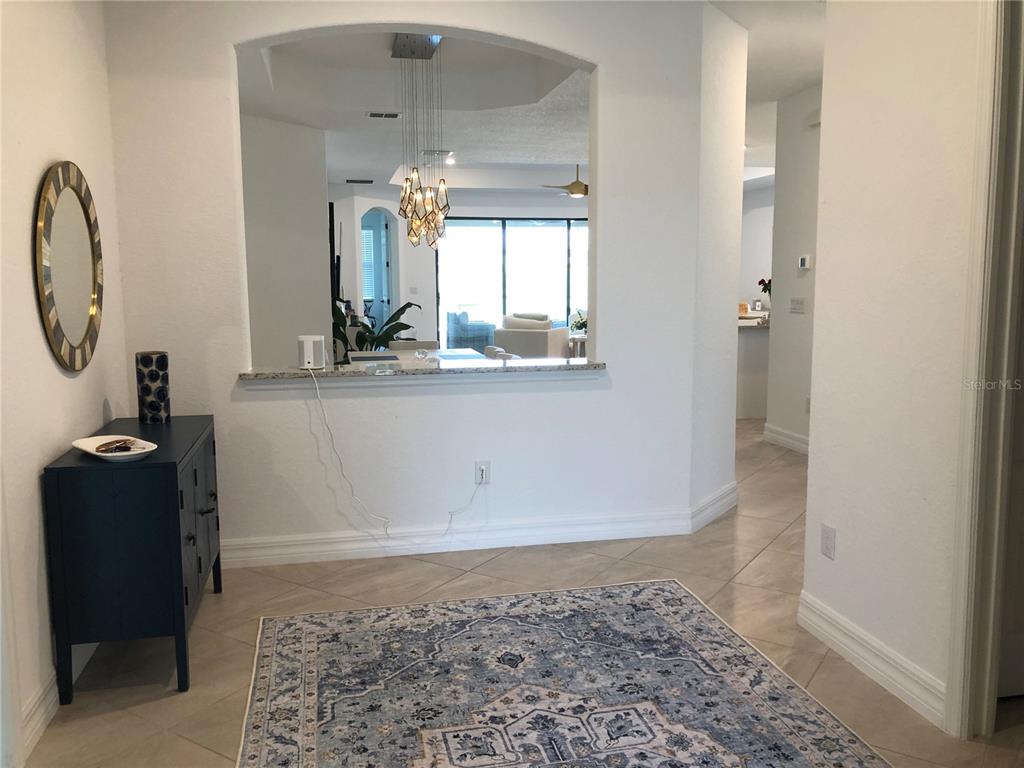 An entryway with a blue cabinet, a patterned rug, and a pass-through to the living area — 5720 CHEECH GLEN, BRADENTON, FL