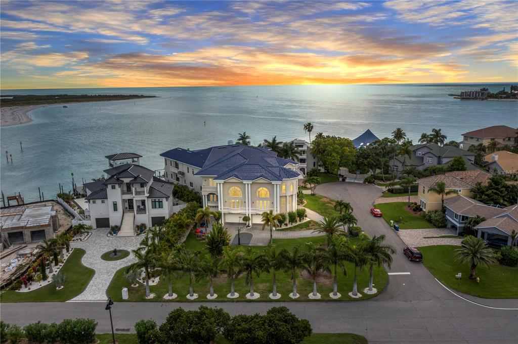 A spacious covered patio features stone flooring, white columns, and a view of the water — 774 NINA DRIVE, TIERRA VERDE, FL