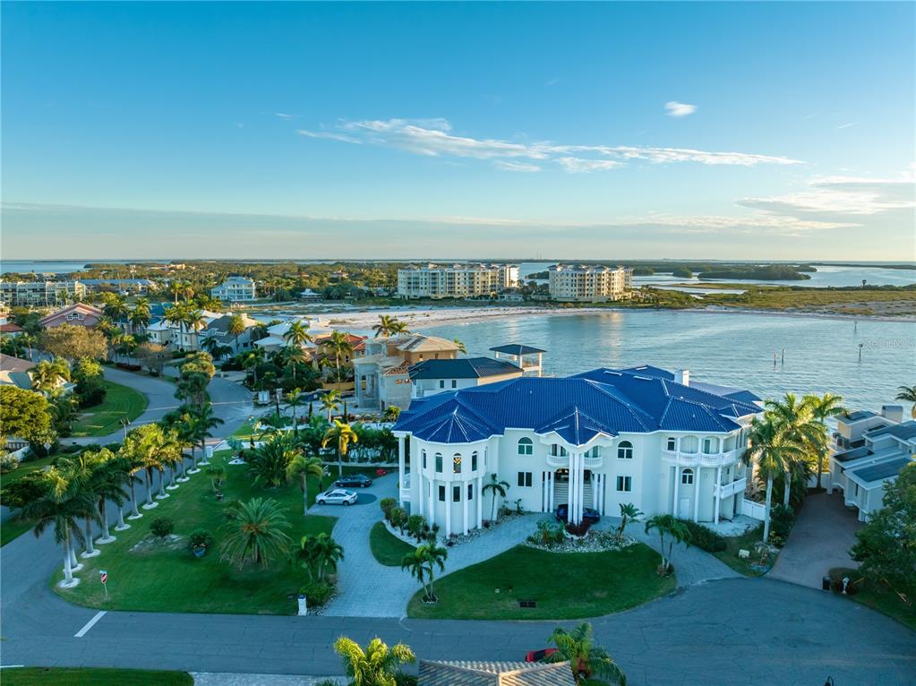 An aerial view of a large, multi-story coastal mansion with a blue roof at sunset — 774 NINA DRIVE, TIERRA VERDE, FL