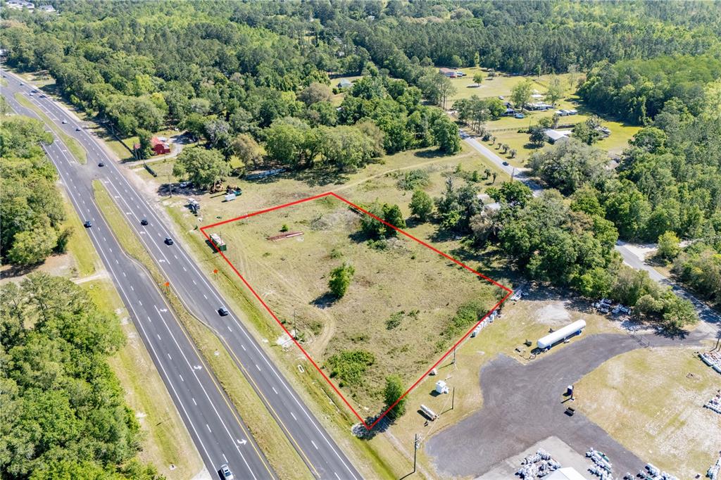 An aerial view shows a vacant, rectangular lot bordered by a highway and trees — 9627 US HIGHWAY 301 HIGHWAY N, HAMPTON, FL