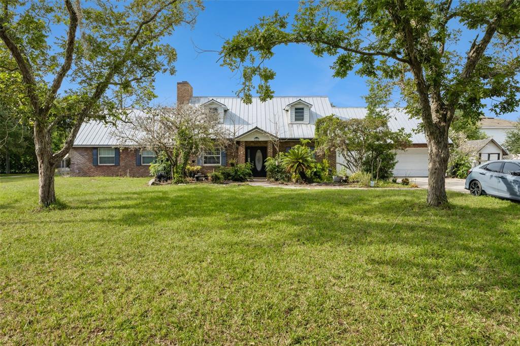A single-story brick house with a metal roof, dormer windows, and a large front lawn — 10605 MOORE ROAD, GOTHA, FL