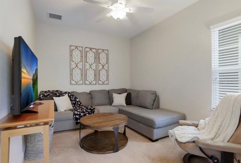 A living room features a gray sectional sofa, a wooden coffee table, and a television — 13012 DEEP BLUE PLACE, BRADENTON, FL