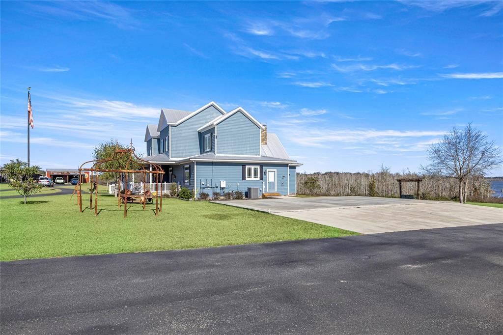 A blue two-story house with a metal roof sits next to a large concrete patio — 5251 SE 180TH AVENUE ROAD, OCKLAWAHA, FL