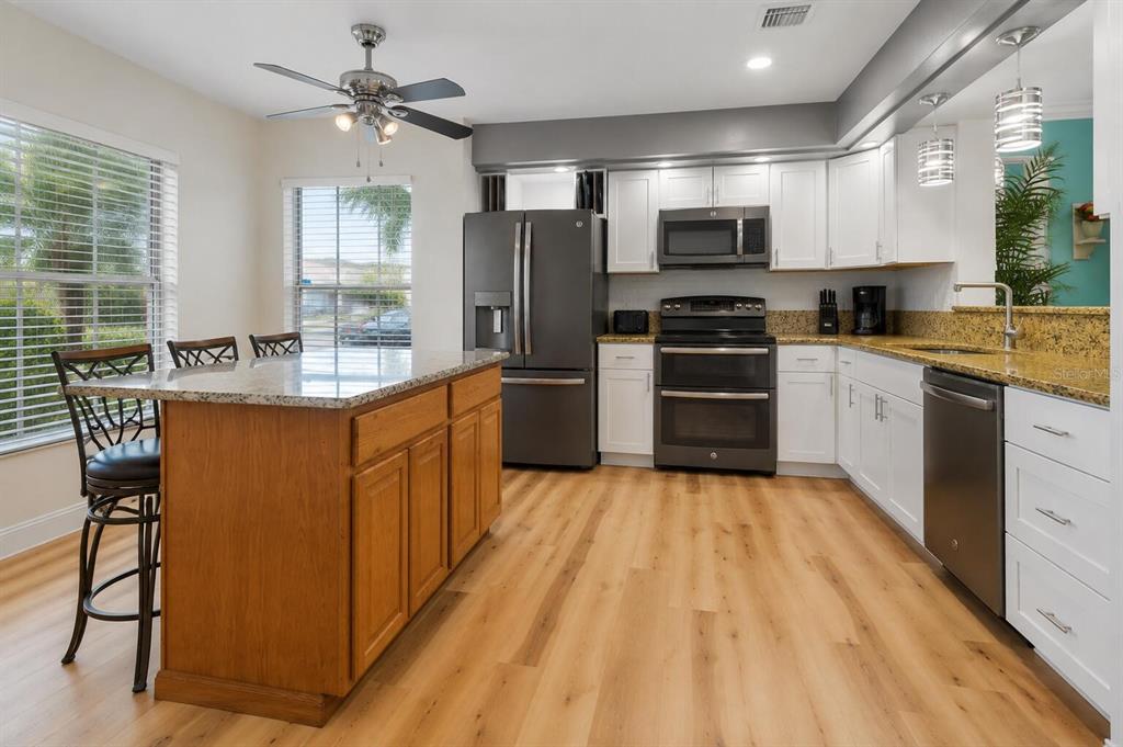 A kitchen features white cabinets, a wooden island, dark appliances, and light wood-look flooring — 125 HIDDEN SPRINGS CIRCLE, KISSIMMEE, FL