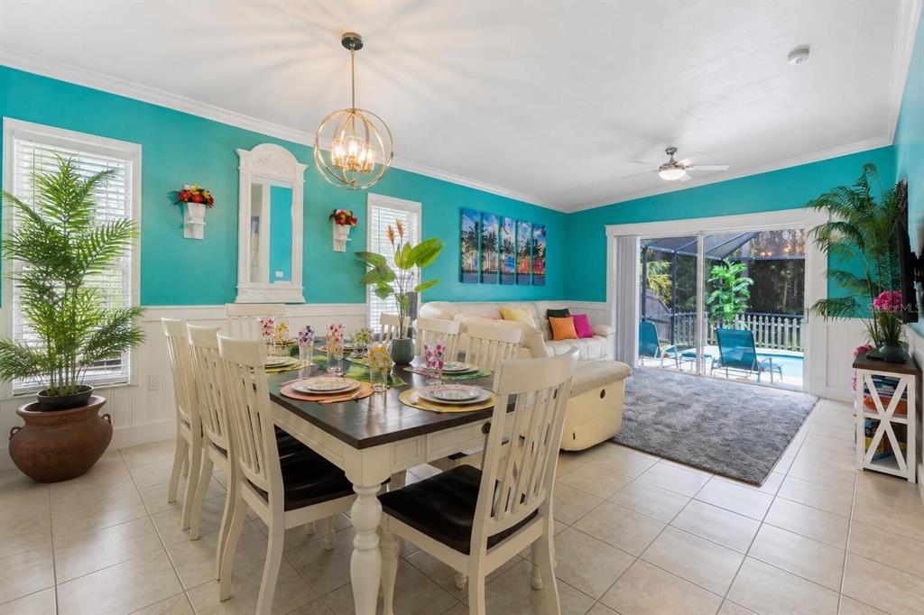 A dining area with a wooden table and white chairs sits before a turquoise living room — 125 HIDDEN SPRINGS CIRCLE, KISSIMMEE, FL
