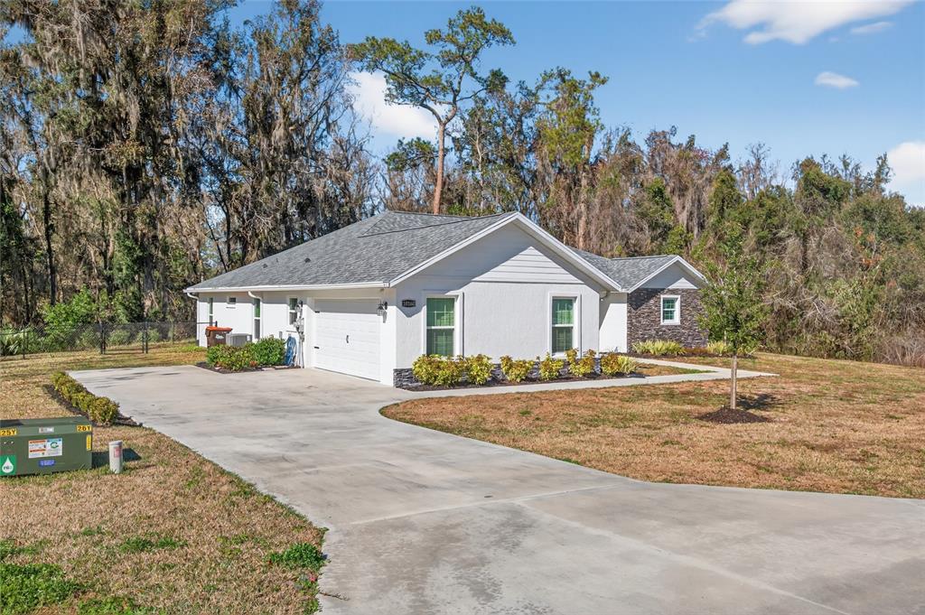 A white single-story house with a gray roof and concrete driveway sits on a grassy lot — 10160 SE 41ST AVENUE, BELLEVIEW, FL