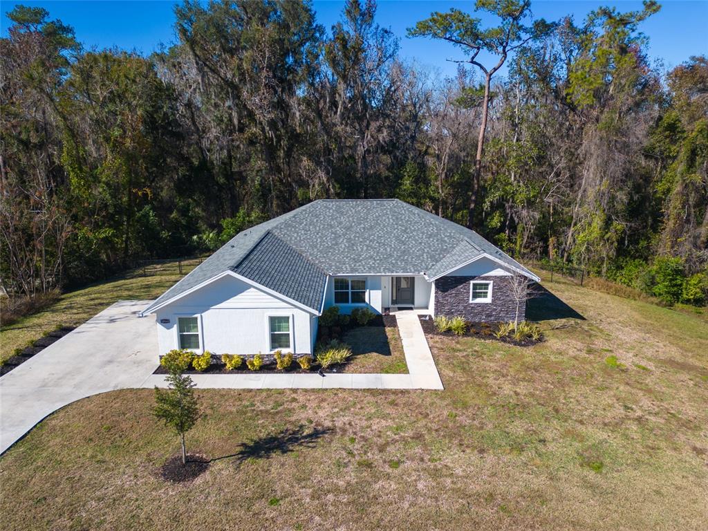 An aerial view shows a single-story house with a gray roof and white and stone siding — 10160 SE 41ST AVENUE, BELLEVIEW, FL