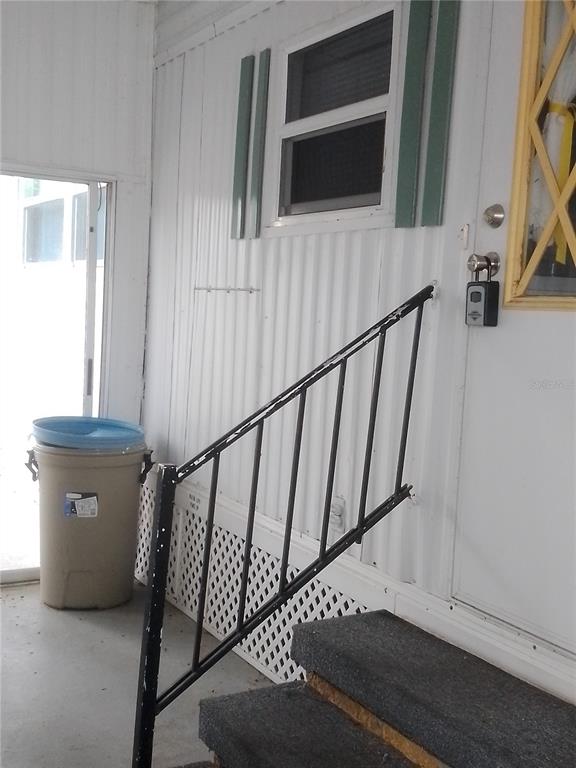 A metal railing leads up concrete steps to a door with a lockbox on a porch — 112 PALM DRIVE UNIT B, EUSTIS, FL