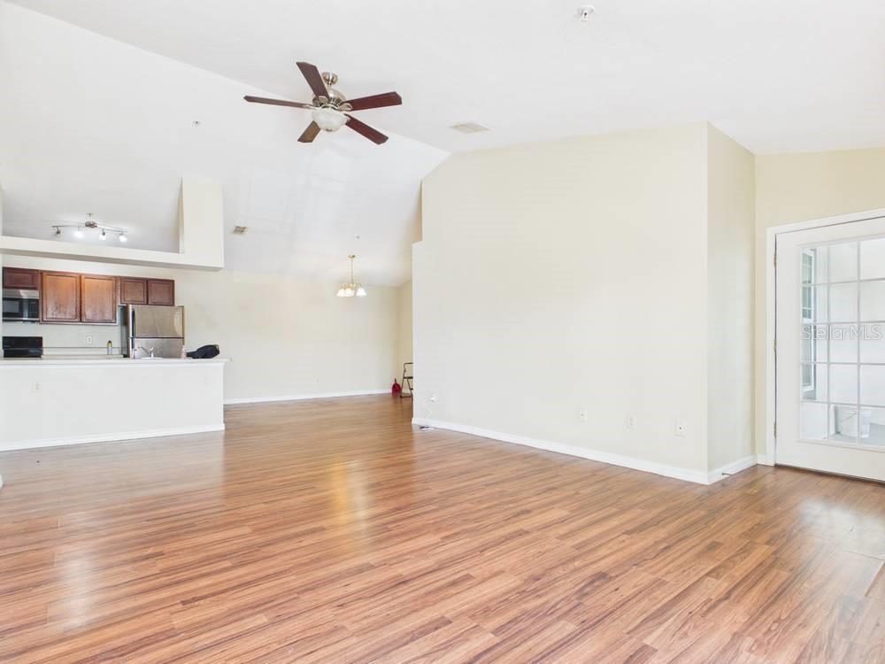 An open-concept living area features wood-look flooring, vaulted ceilings, and an adjacent kitchen — 16337 ENCLAVE VILLAGE DRIVE UNIT 16337, TAMPA, FL