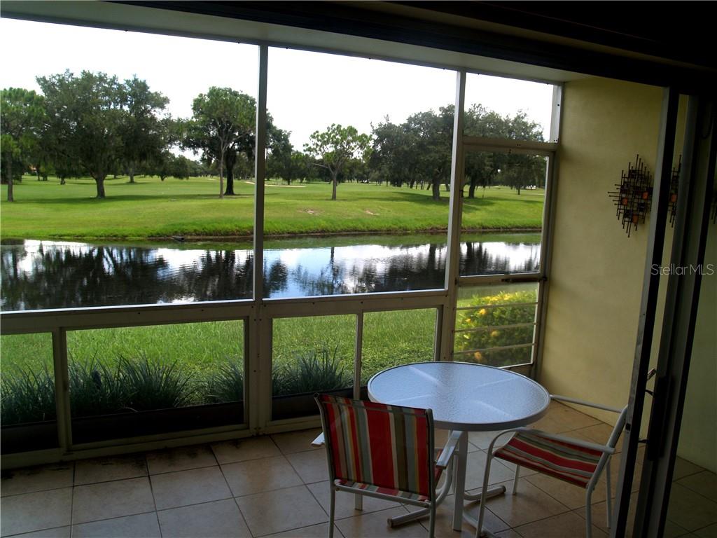 A screened-in patio overlooks a pond and a golf course with scattered trees — 7405 W COUNTRY CLUB DRIVE N UNIT 104, SARASOTA, FL