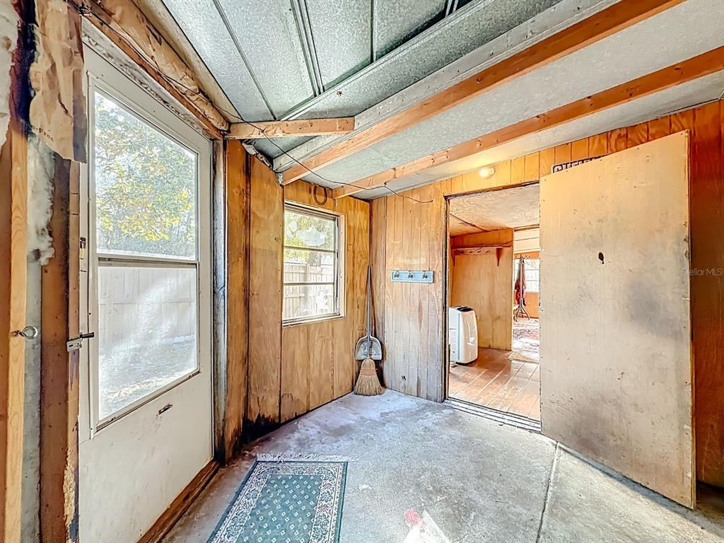 A rustic, unfinished room features wood-paneled walls, a concrete floor, and a metal ceiling — 3180 E BUFFALO LANE, HERNANDO, FL