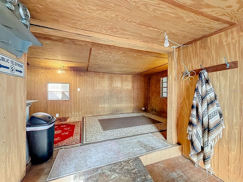A rustic room features plywood walls, a raised platform area, and several area rugs — 3180 E BUFFALO LANE, HERNANDO, FL