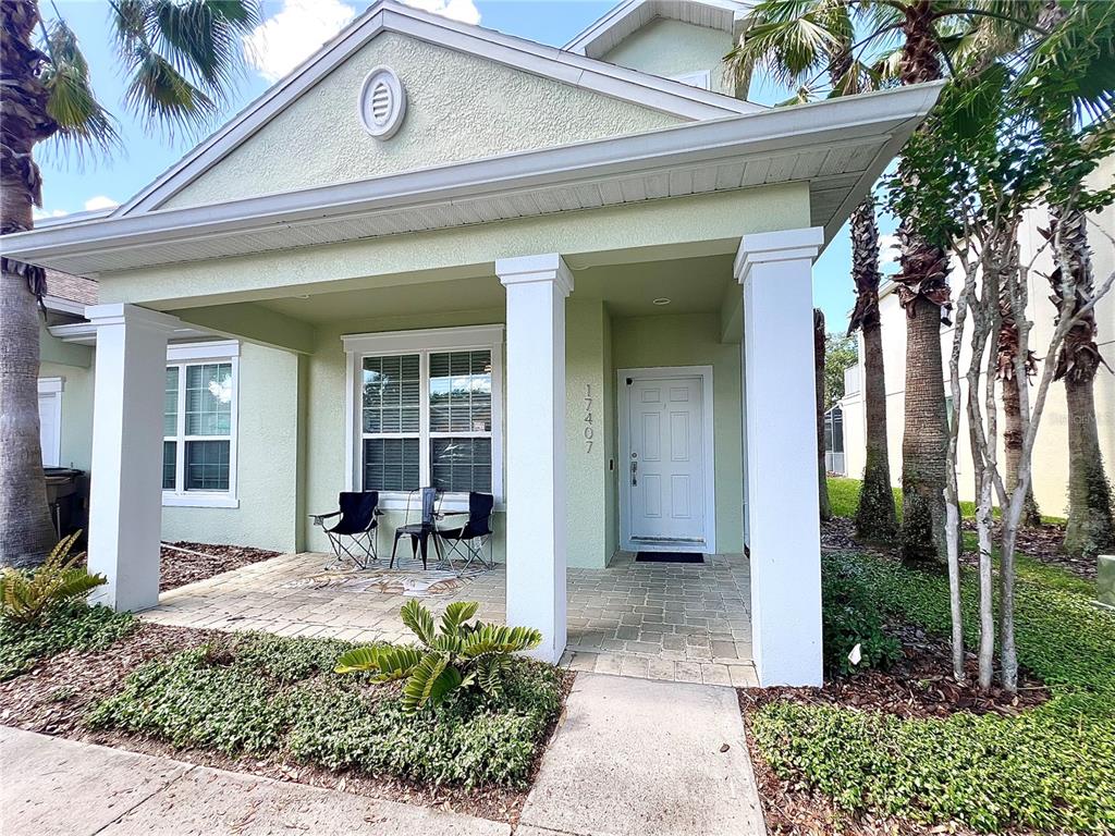 A light green house exterior features a covered front porch with white columns and pavers — 17407 PLACIDITY AVENUE, CLERMONT, FL