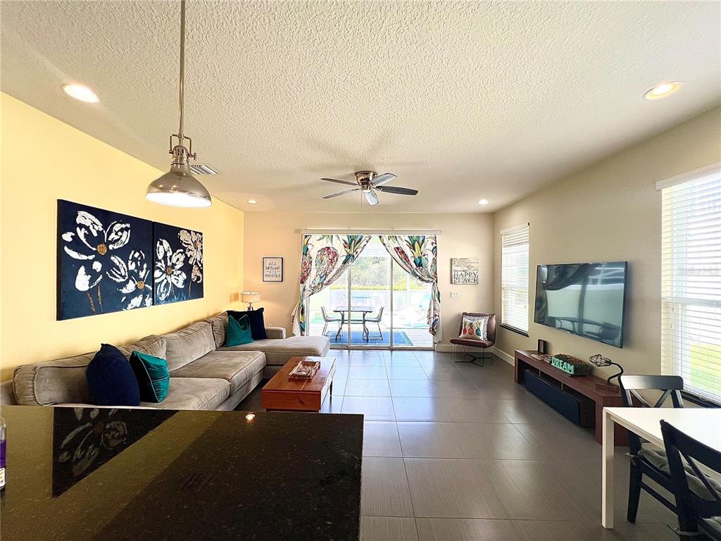 A living room features a grey sectional sofa, tile flooring, and sliding glass patio doors — 17407 PLACIDITY AVENUE, CLERMONT, FL
