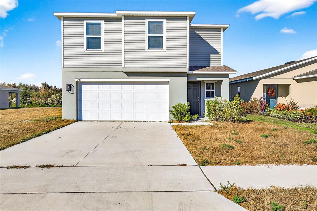 A two-story house with gray siding, a white garage door, and a concrete driveway — 1753 EAGLE HAMMOCK BOULEVARD, EAGLE LAKE, FL