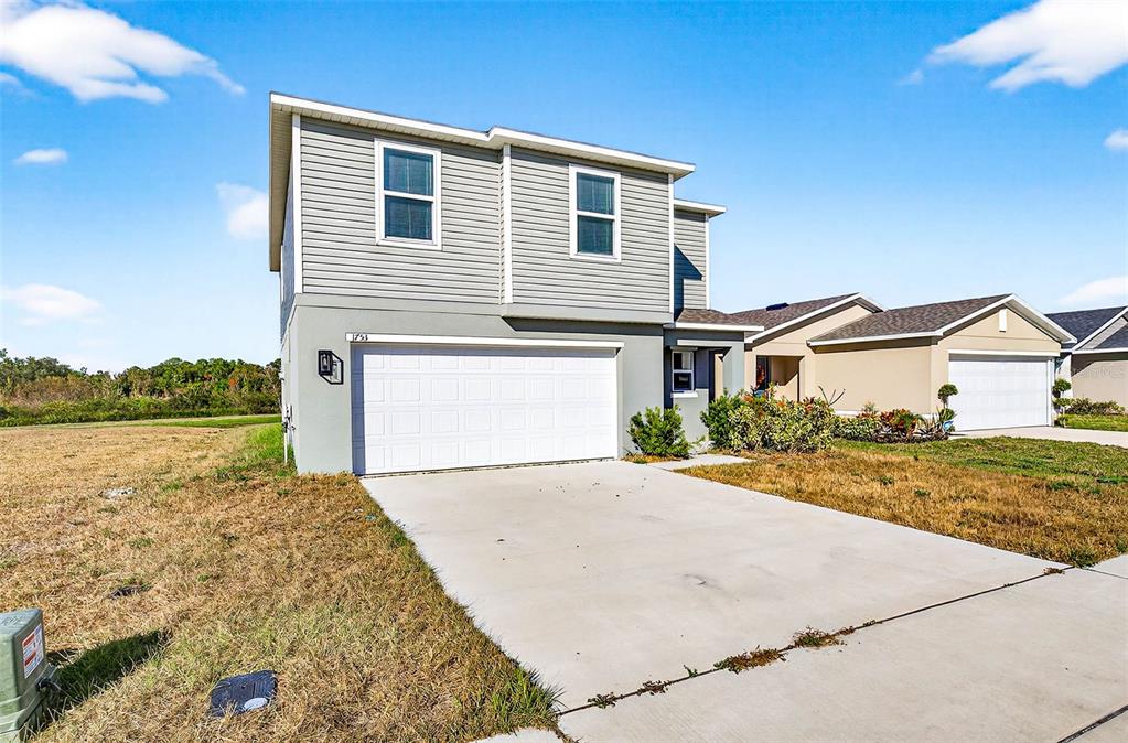 A two-story house with gray siding, a white garage door, and a concrete driveway — 1753 EAGLE HAMMOCK BOULEVARD, EAGLE LAKE, FL