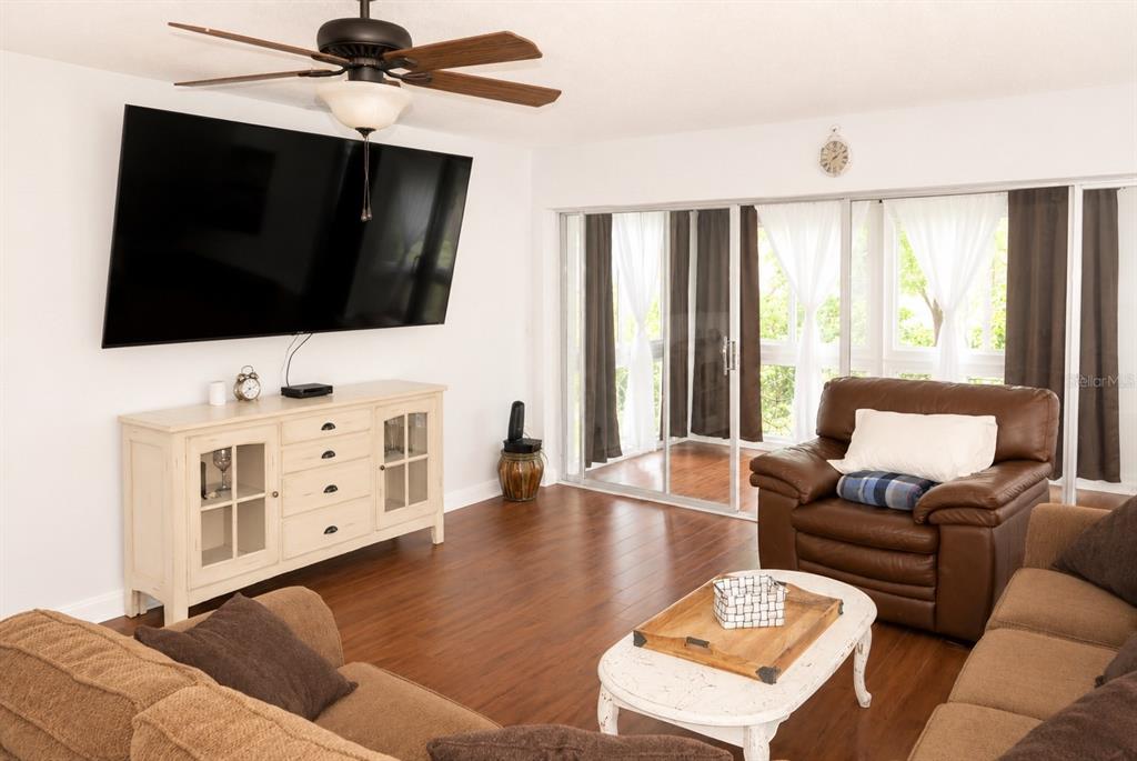 A living room features a large television, a ceiling fan, and a brown leather armchair — 19029 US HIGHWAY 19 N UNIT 2-22, CLEARWATER, FL
