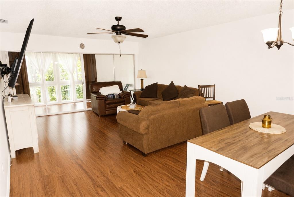 A living room and dining area feature wood-look flooring, a brown sofa, and a ceiling fan — 19029 US HIGHWAY 19 N UNIT 2-22, CLEARWATER, FL