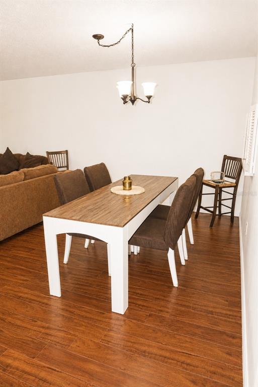 A dining area features a wooden table with white legs, brown chairs, and wood flooring — 19029 US HIGHWAY 19 N UNIT 2-22, CLEARWATER, FL