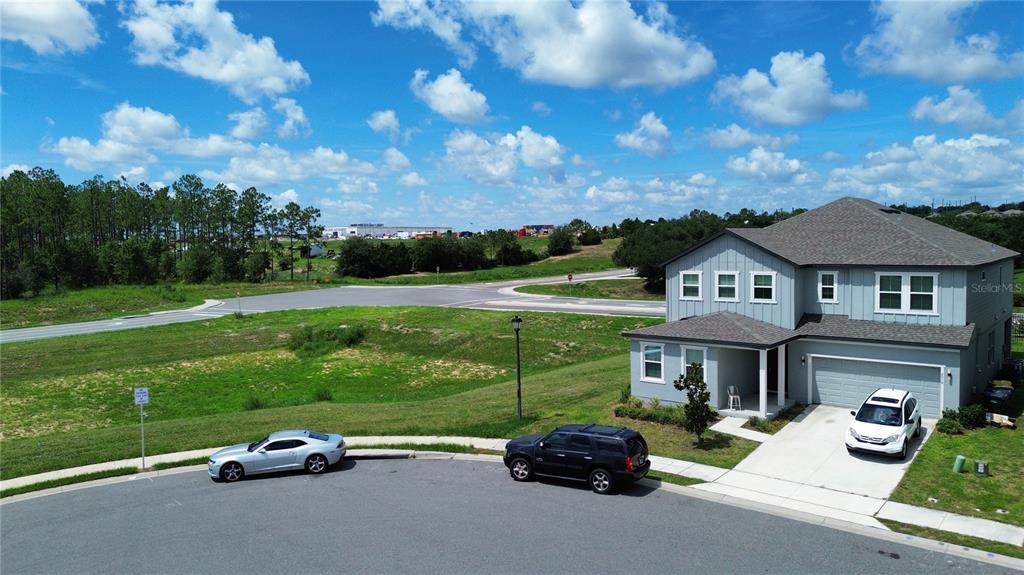 An aerial view shows a two-story gray house with a driveway and two parked cars — 2018 DERWENT DRIVE, DAVENPORT, FL