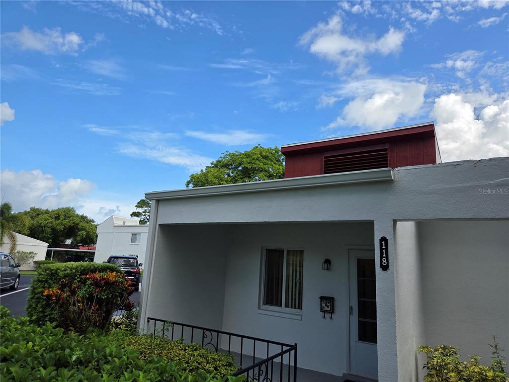 The exterior of a single-story residential building features a covered entryway and address number 118 — 2060 MARILYN STREET UNIT 118, CLEARWATER, FL