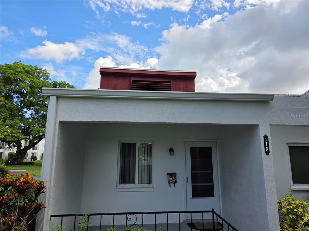 The exterior of a white one-story building features a covered porch and a red vent — 2060 MARILYN STREET UNIT 118, CLEARWATER, FL