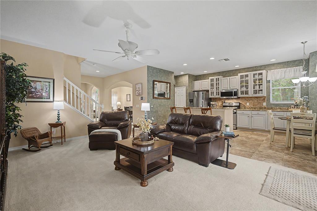 A living room with beige carpet, a light-colored sofa, two side tables, and an arched entryway — 8711 PRESTON WOODS COURT, LAND O LAKES, FL