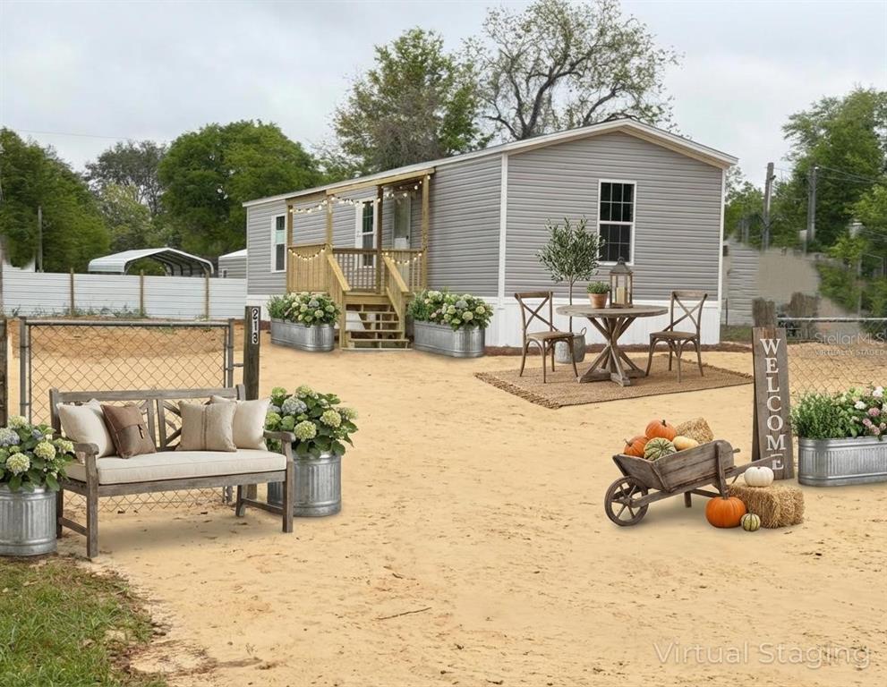 This is a digitally staged exterior view of a manufactured home with a sandy yard — 213 MILTON AVENUE, INTERLACHEN, FL